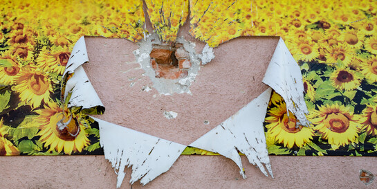 Zerstörung durch Krieg in der Ukraine an einer Hauswand mit Sonnenblumen-Tapete