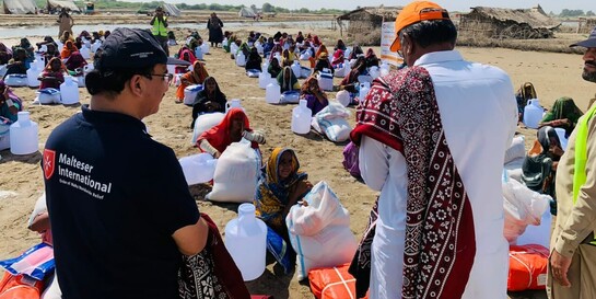 Helfer der Organisation Malteser International versorgen die von der Flut betroffenen Menschen mit Wasser und Lebensmittel