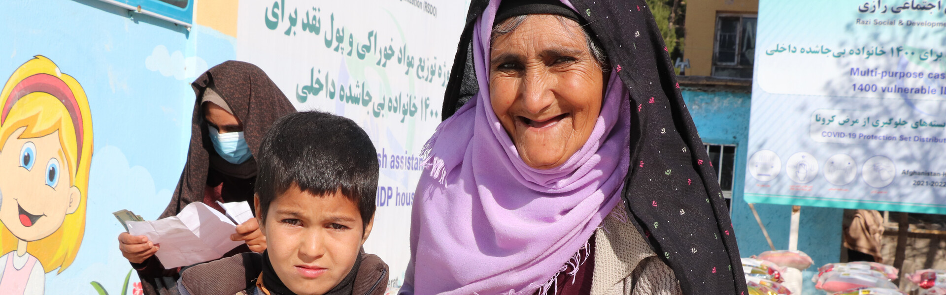 Eine Frau steht neben einem Jungen bei einer Lebensmittelverteilung in Afghanistan
