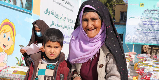 Eine Frau steht neben einem Jungen bei einer Lebensmittelverteilung in Afghanistan