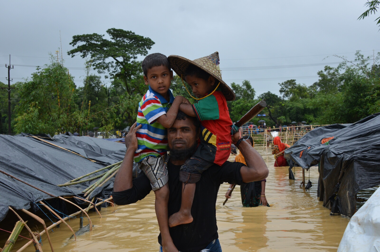 Ein Mann mit seinen Kindern in einem überfluteten Flüchtlingscamp in Bangladesch