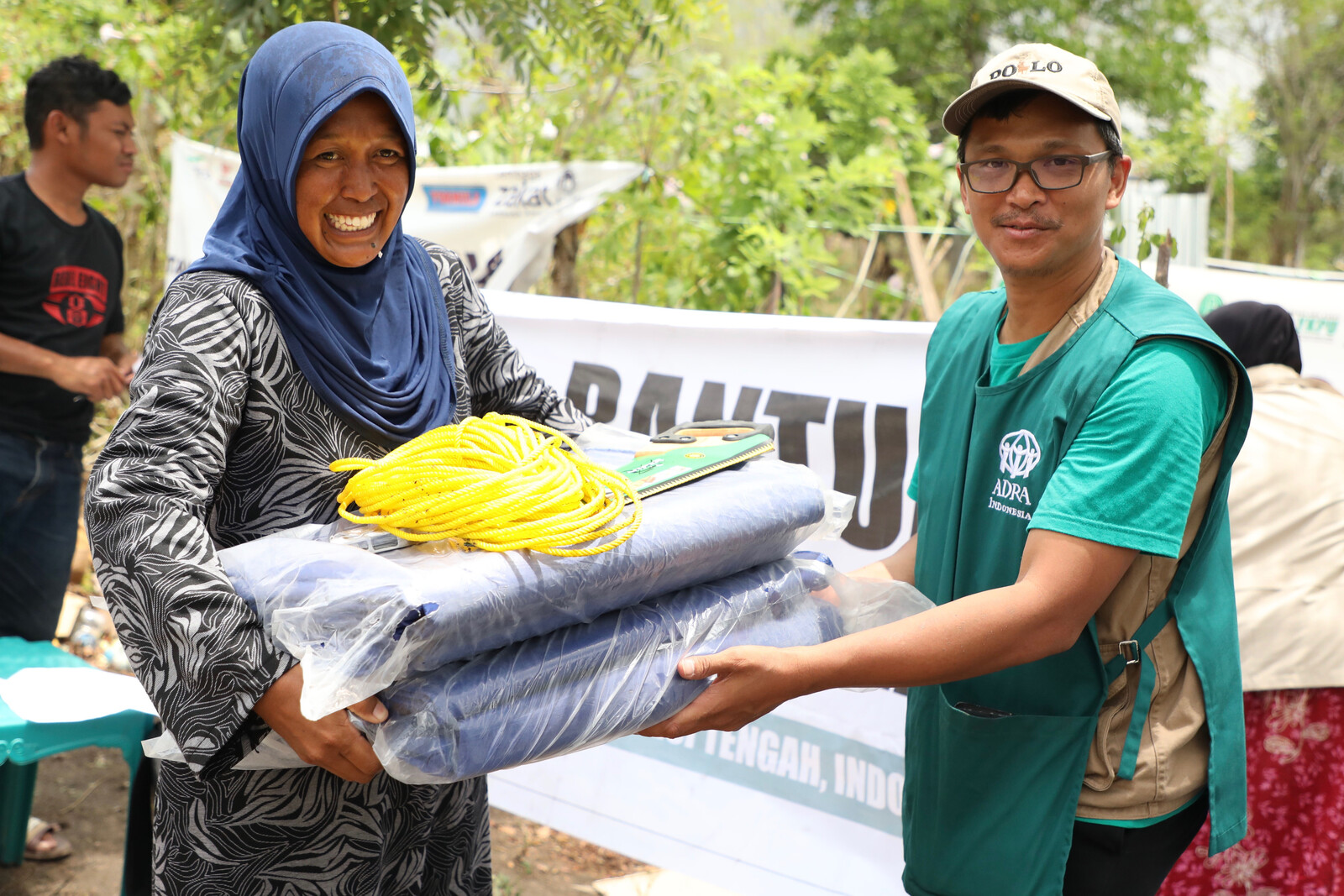 Ein Helfer von ADRA übergibt einer Frau auf Sulawesi Hilfsgüter.