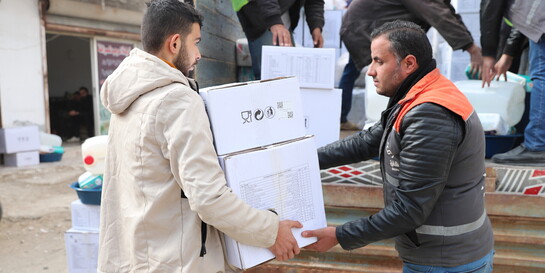 Helfer übergibt Hilfspaket an Mann in Syrien