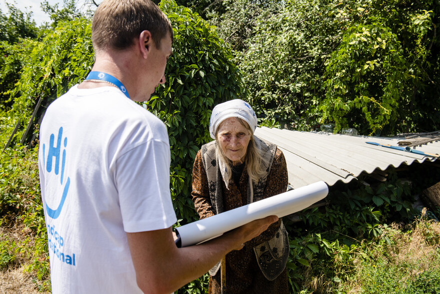 Ein Helfer von Handicap International klärt eine ältere Frau über Minen auf