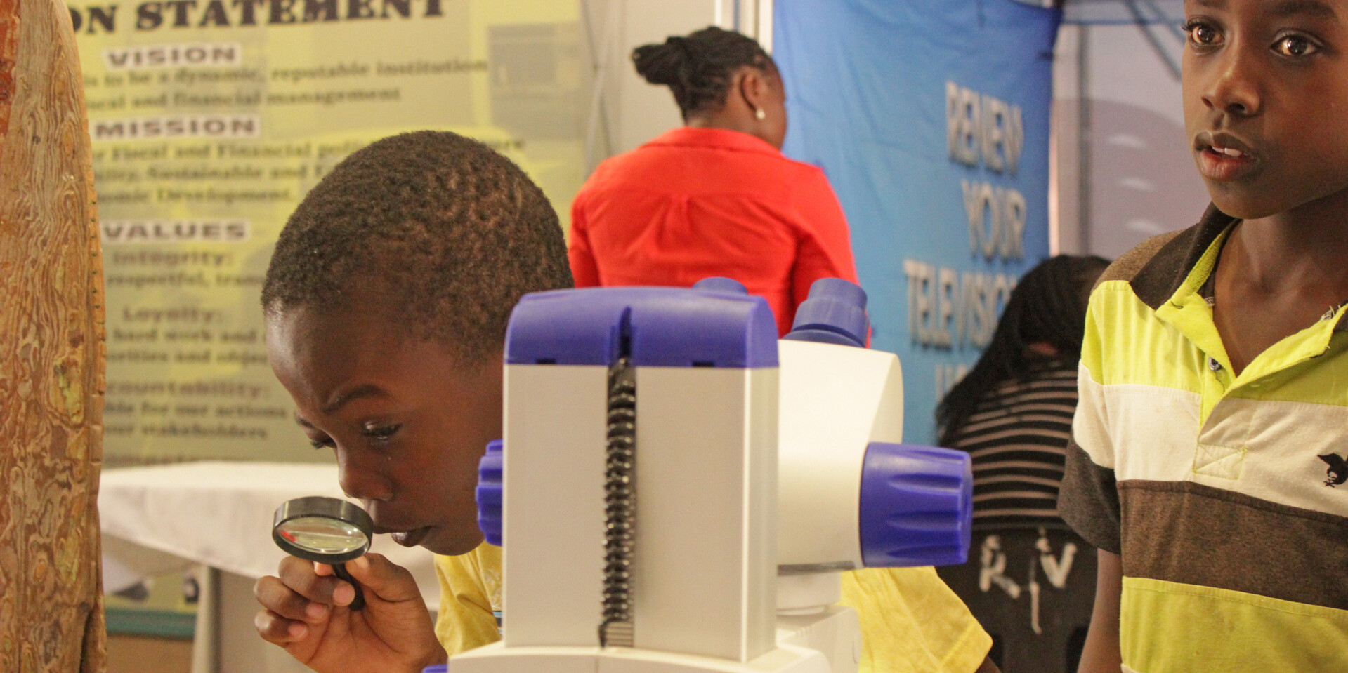 Im Museum beobachtet ein Schüler aus Namibia das Ausstellungsstück mit der Lupe