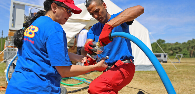 Helfer installieren eine Wasserfiltrationsanlage in einem Flüchtlingscamp Helfer installieren eine Wasserfiltrationsanlage in einem Flüchtlingscamp