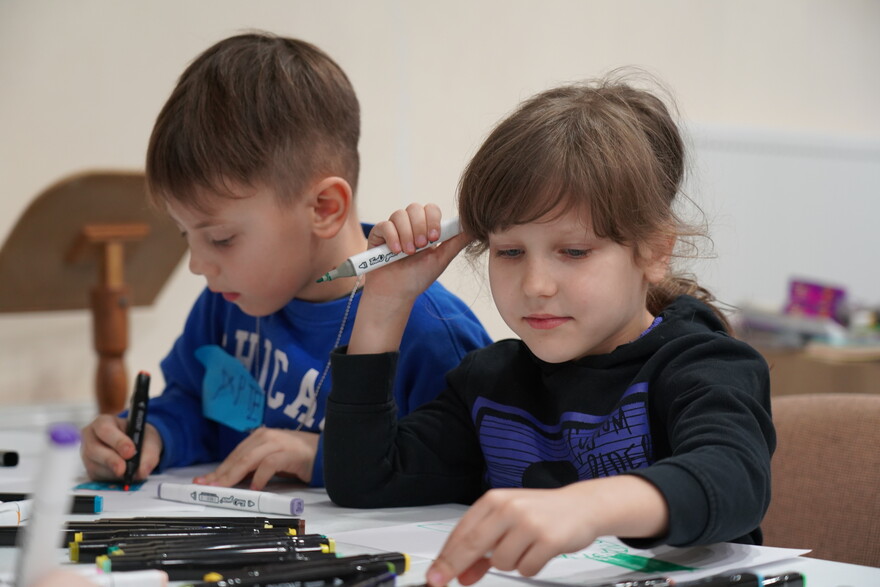 Ein Junge und ein Mädchen sitzen am Tisch und malen