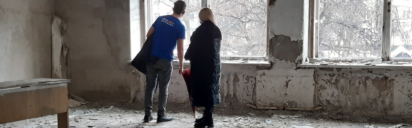 Ukraine Krieg: Ein Mann und eine Frau stehen in einem zerstörten Haus