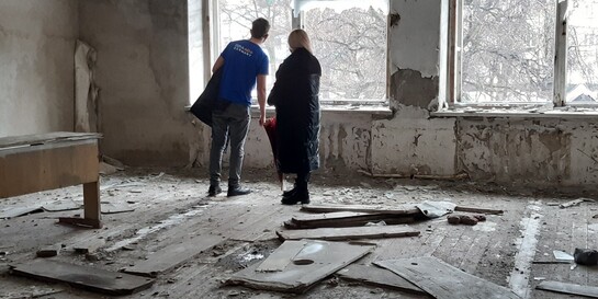 Ukraine Krieg: Ein Mann und eine Frau stehen in einem zerstörten Haus