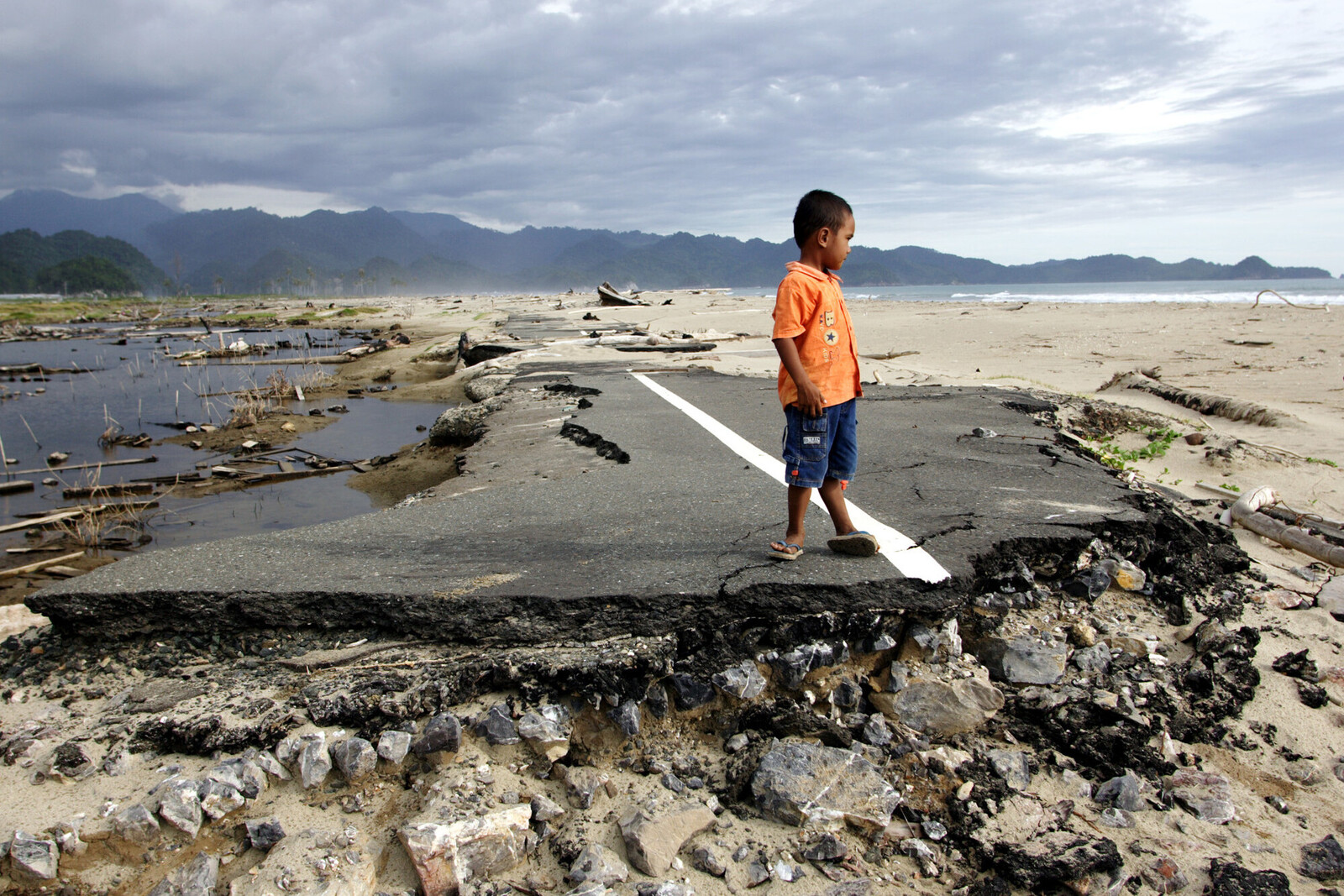 Kind auf einer durch den Tsunami 2004 zerstörten Straße auf Sumatra, Indonesien