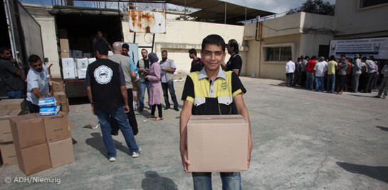 Syrischer Junge trägt ein Paket mit Hilfslieferungen