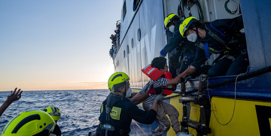Geflüchtete werden auf Rettungsboot gezogen
