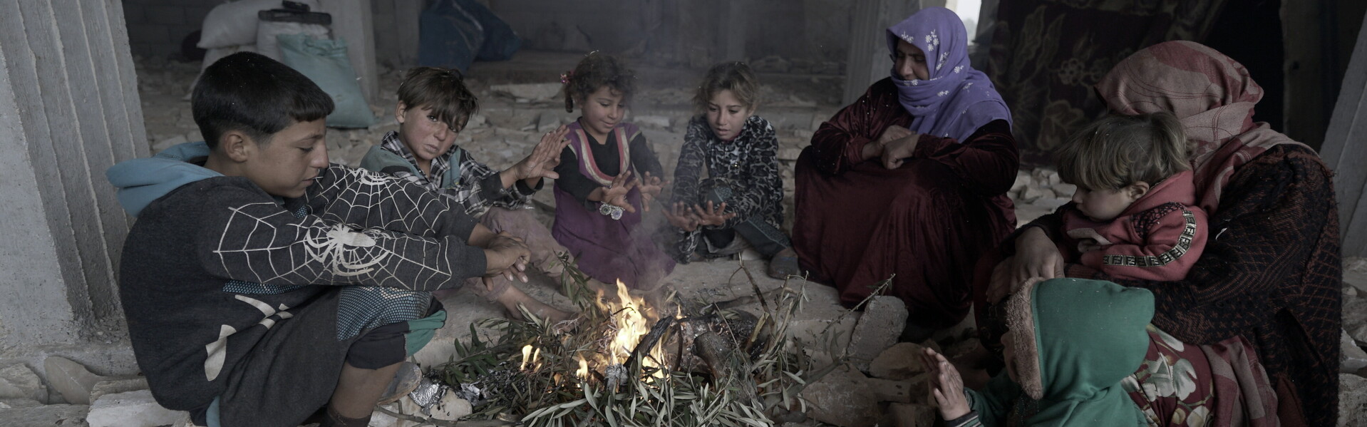 Syrische Flüchtlingskinder und Frauen wärmen sich am Feuer 