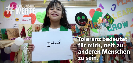 Kind hält Schild hoch mit der Aufschrift Toleranz.