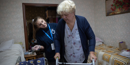 Eine Helferin von Handicap International behandelt eine Frau mit Gehhilfe