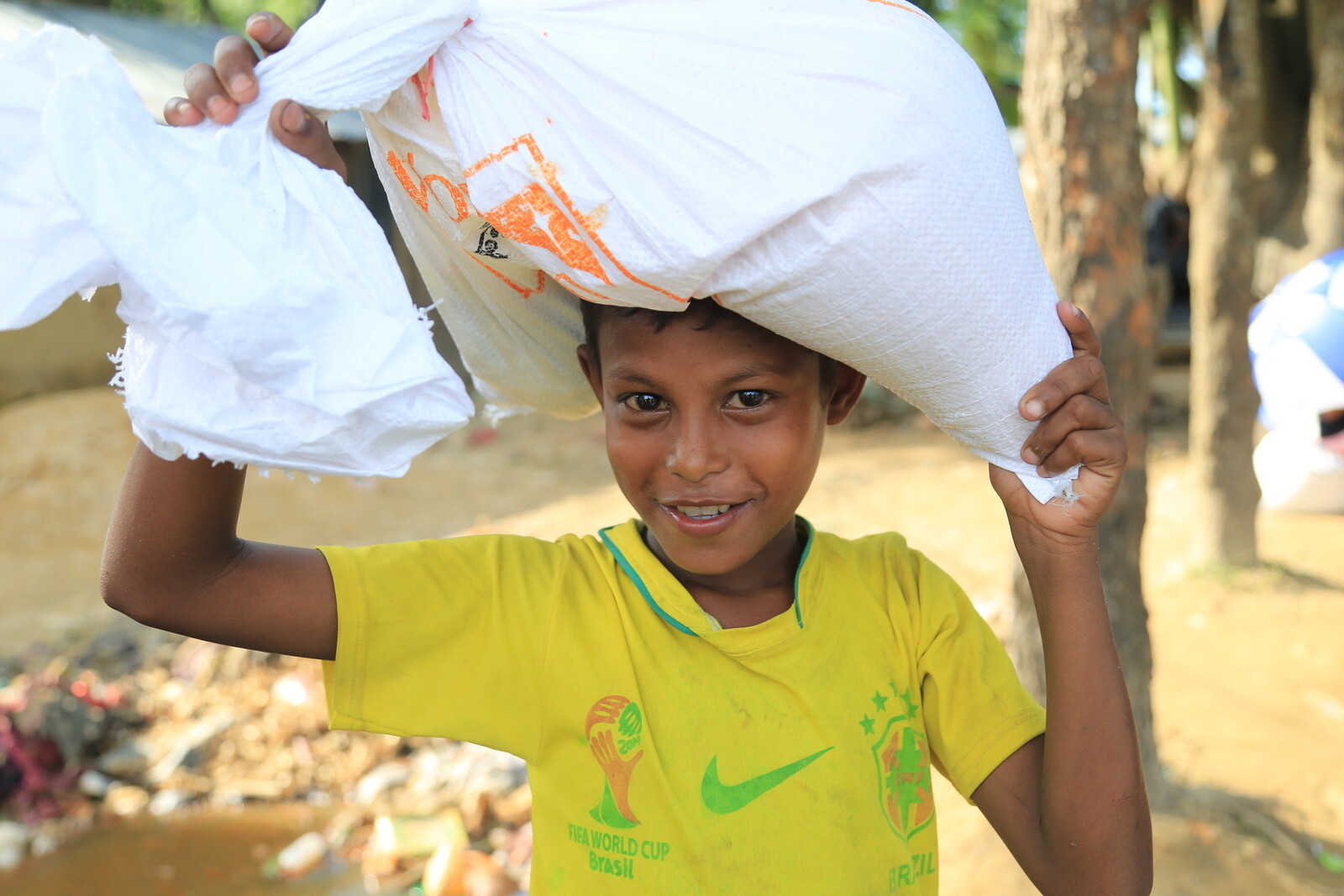 In einem Flüchtlingscamp in Bangladesch trägt ein Junge Hilfsgüter