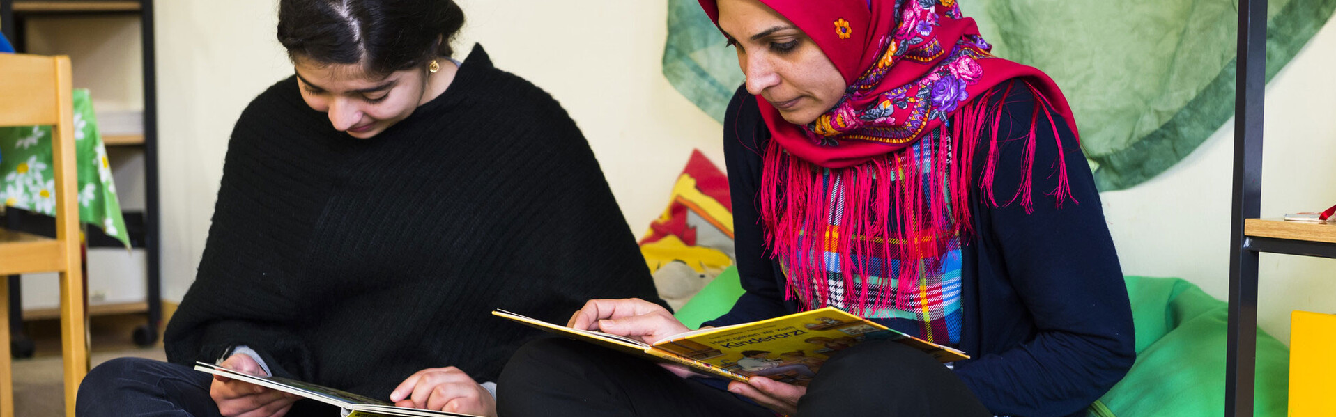 Zwei geflüchtete Frauen lesen in einer Unterkunft Zwei geflüchtete Frauen lesen in einer Unterkunft