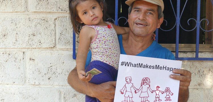 In Guatemala hält ein Mann, mit Kind im Arm, ein Zettel mit der Aufschrift "#whatmakesmehappy" und dass ihm die Familie am wichtigsten ist