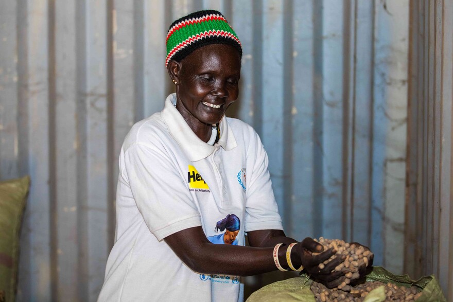 Eine lächelnde Frau im Südsudan mit Saatgut in den Händen