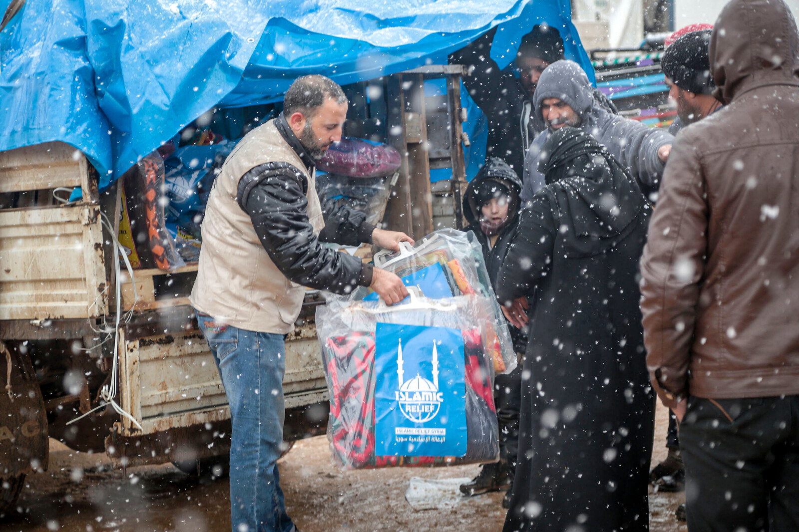 Helfer verteilen Decken und warme Kleidung an syrische Flüchtlinge.