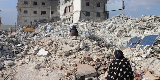Menschen sitzen nach einem Erdbeben in Syrien auf Trümmern (Symbolbild)