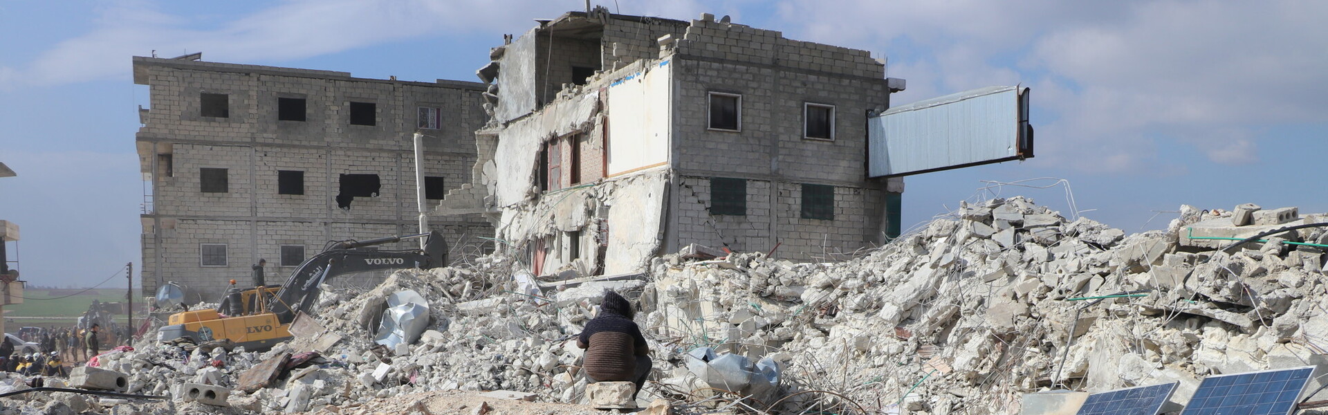 Menschen sitzen nach einem Erdbeben in Syrien auf Trümmern (Symbolbild)