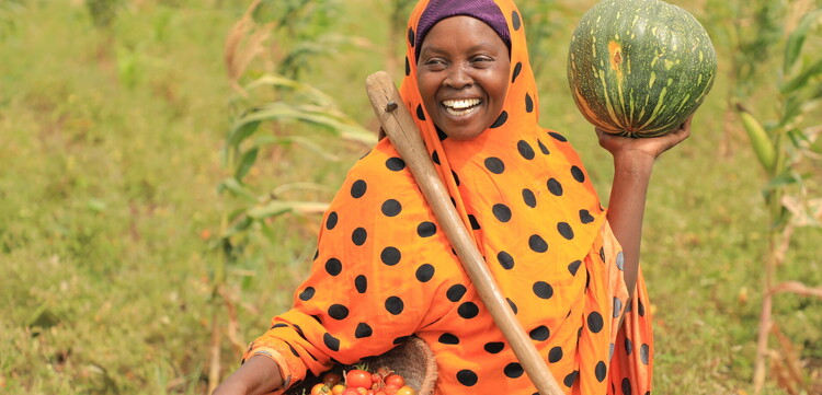 Eine Frau steht in Somalia mit frisch geerntetem Obst und Gemüse auf dem Feld Eine Frau steht in Somalia mit frisch geerntetem Obst und Gemüse auf dem Feld