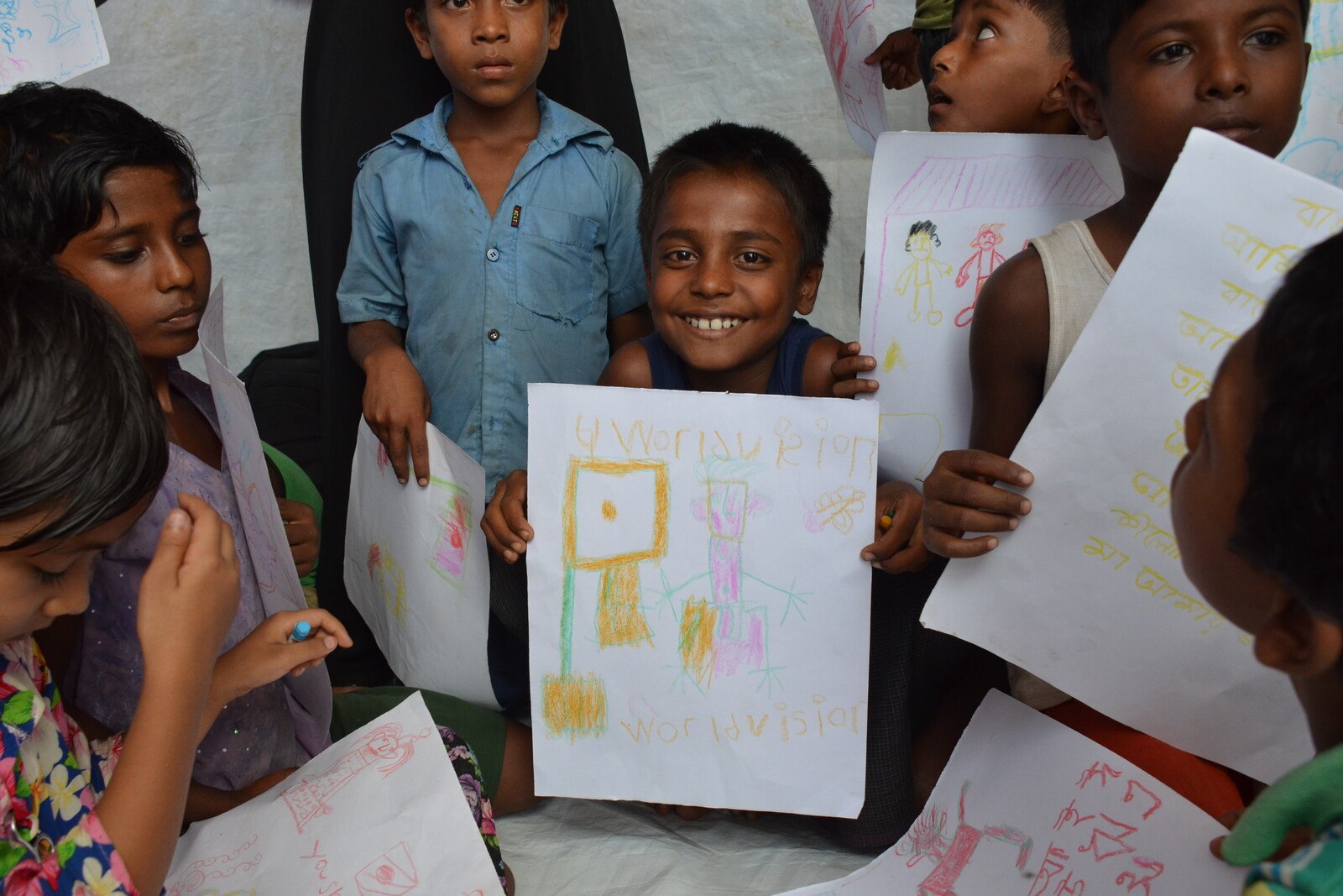 Kinder mit ihren gemalten Bildern in einem Flüchtlingscamp in Bangladesch