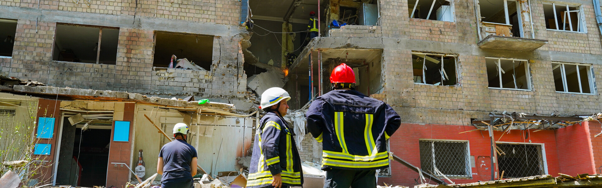 Feuerwehrmänner stehen vor einem zerbombten Wohnhaus in Kiew