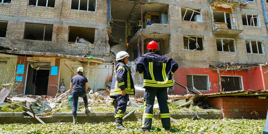 Feuerwehrmänner stehen vor einem zerbombten Wohnhaus in Kiew