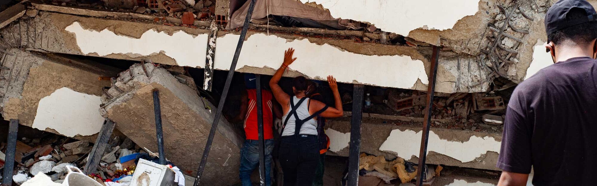Eine Frau und ein Mann stehen vor einem zerstörten Gebäude in Venezuela
