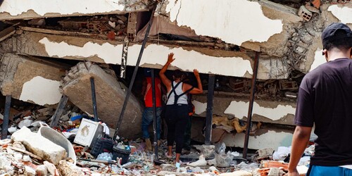 Eine Frau und ein Mann stehen vor einem zerstörten Gebäude in Venezuela