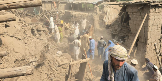 Ein Mann steht inmitten von Gebäuden, die bei dem Erdbeben in Afghanistan zerstört wurden