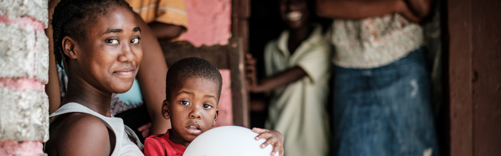 Eine Frau hat in Haiti einen Jungen auf ihrem Schoß sitzen