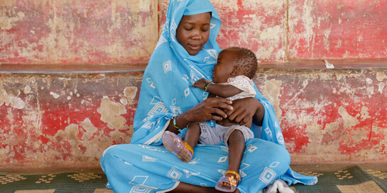 Eine Frau aus dem Sudan hält ihr schreiendes Kind im Arm