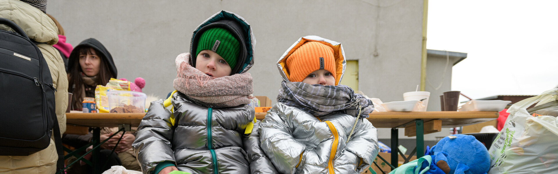 Zwei aus der Ukraine geflüchtete Kinder sitzen auf einer Bank.