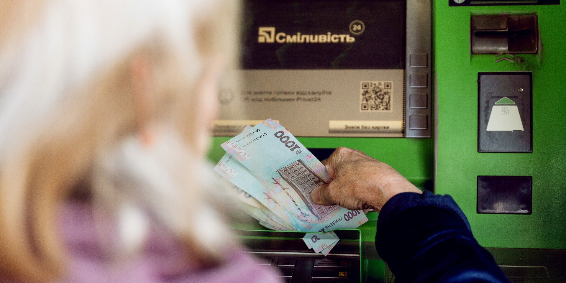 Eine Frau hebt Bargeld an einem Bankautomaten ab