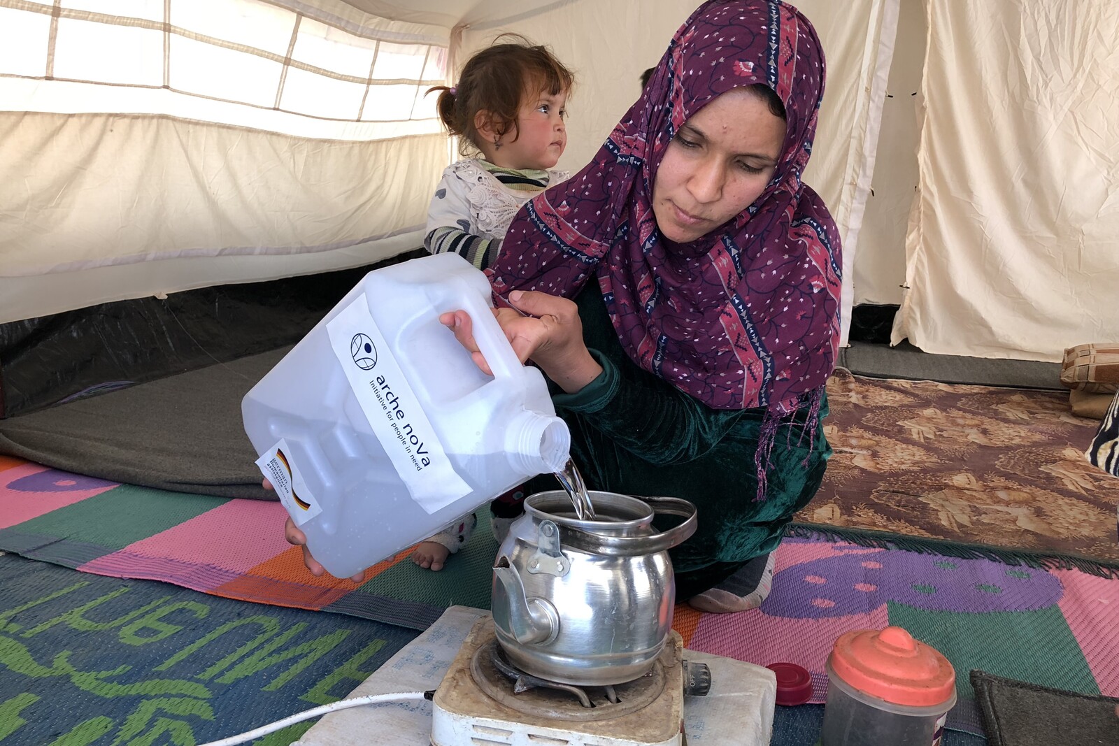 Eine Frau in einem irakischen Flüchtlingscamp hat sauberes Wasser erhalten und kocht damit Tee.