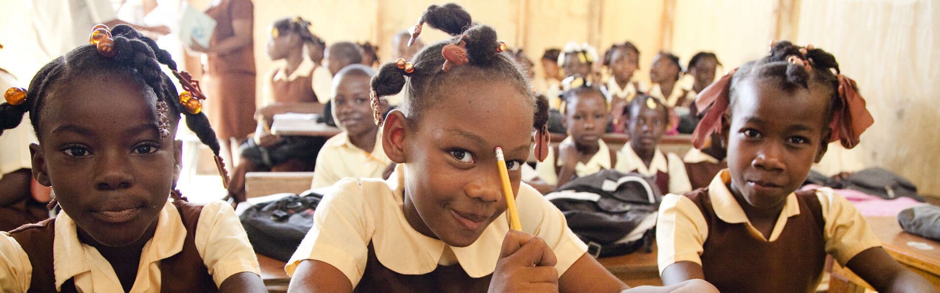 Drei Schülerinnen sitzen an ihren Aufgaben in einer Schule in Haiti