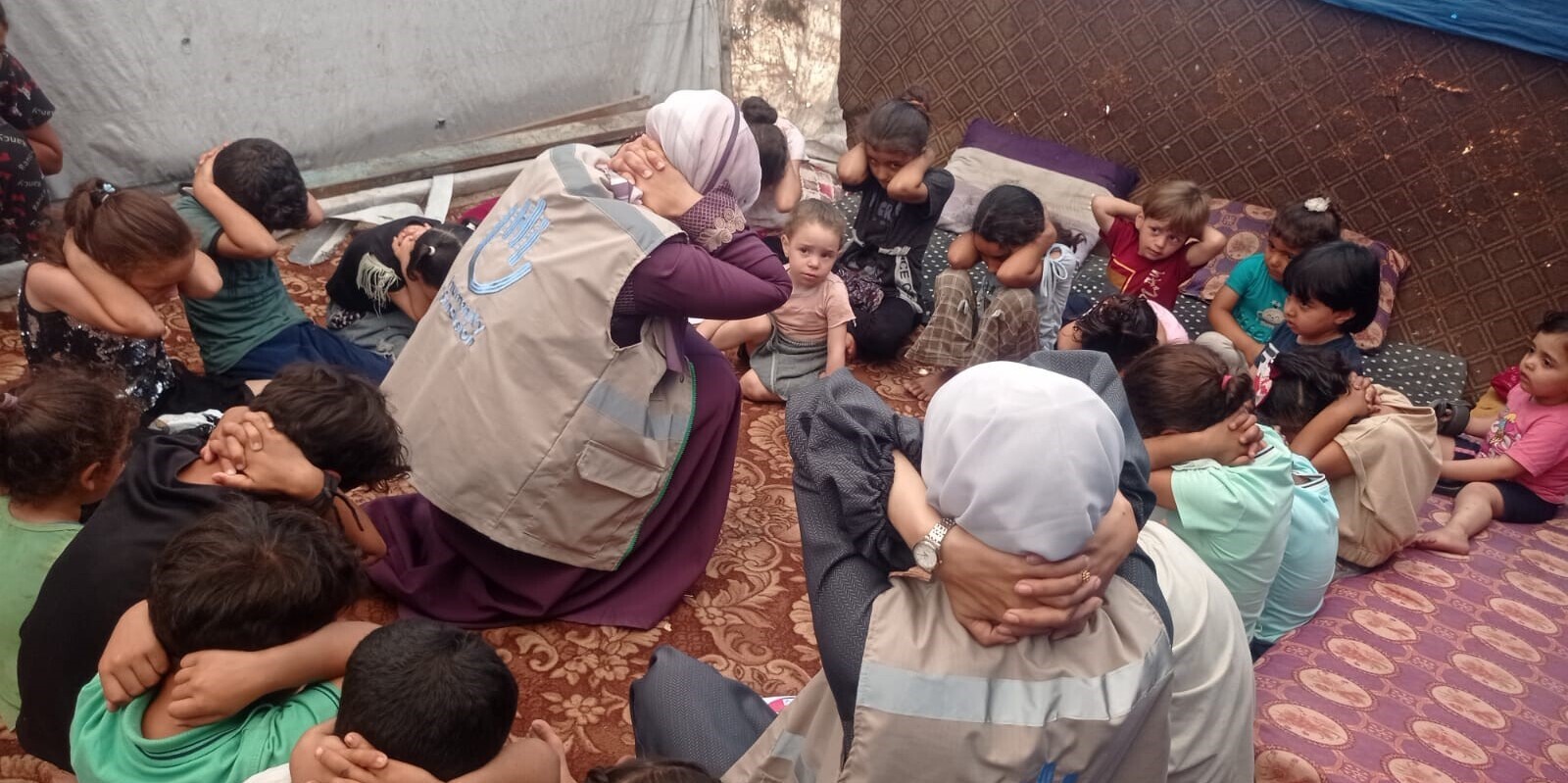 Helferinnen von Handicap International schulen Kinder im richtigen Verhalten bei Bombenangriffen 