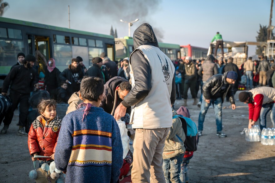 Helfer begleiten Kinder zu den Bussen
