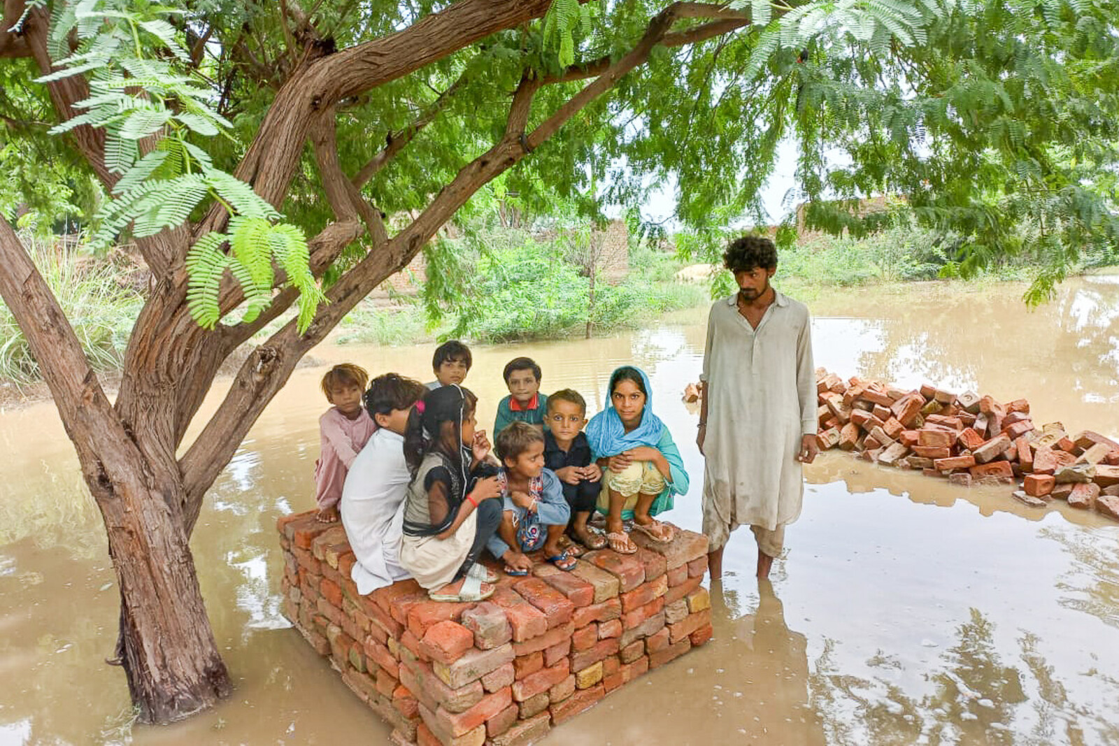 Kinder haben sich vor den Wassermassen auf die Überreste eines Hauses gerettet