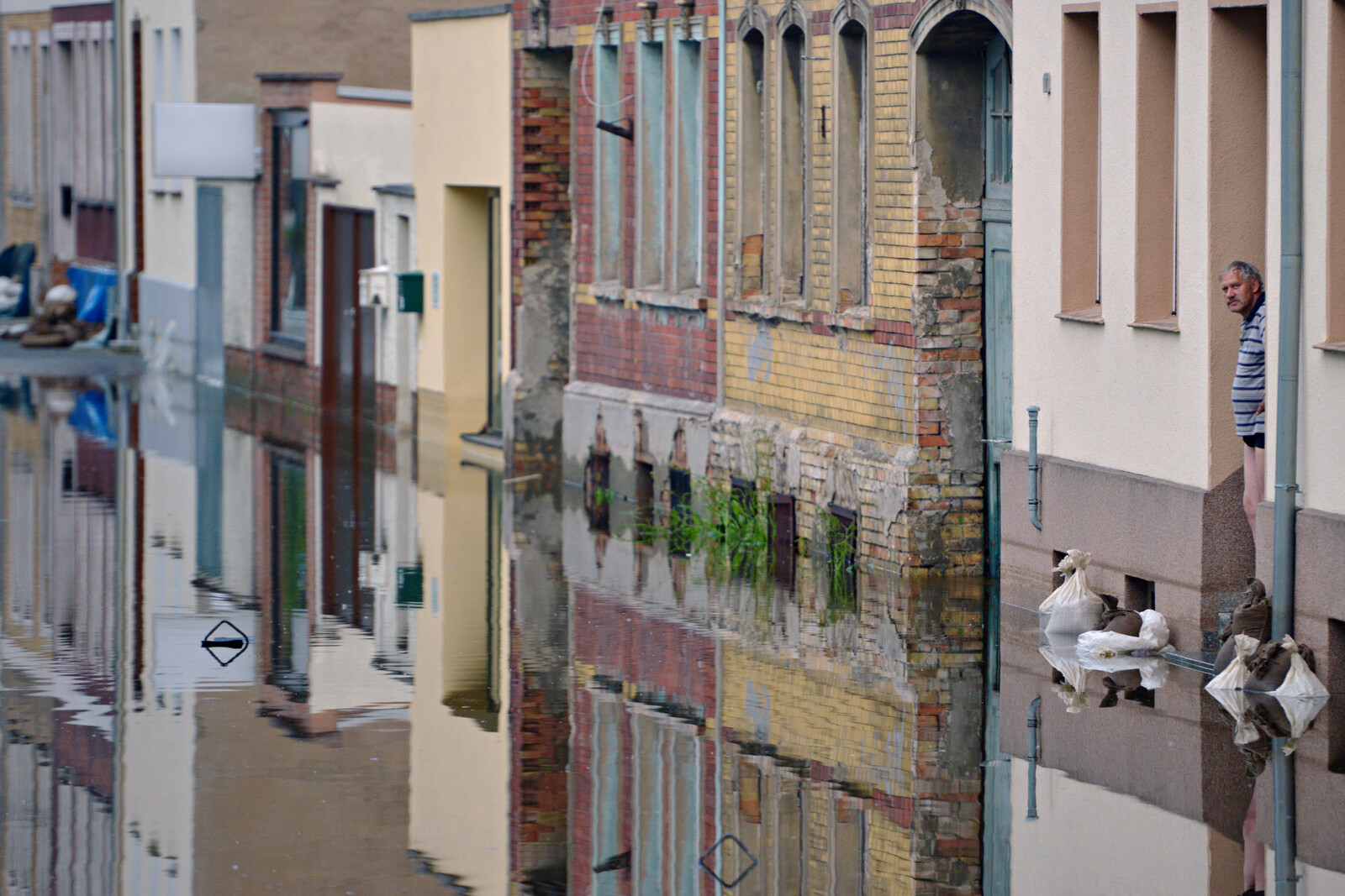 Ein Mann in der sächsischen Stadt Aken schaut aus seiner Haustür hinaus auf die überfluteten Straßen