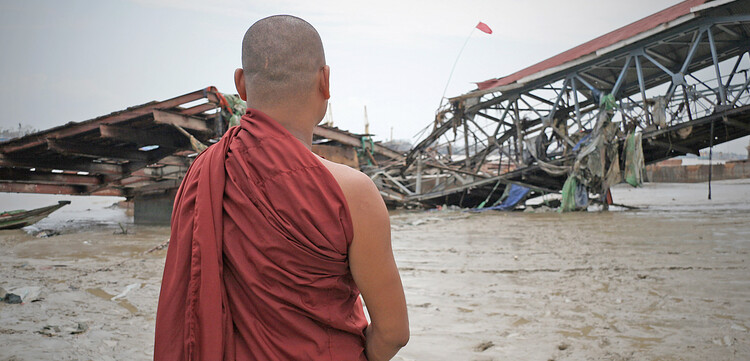 Ein Mönch in Birma blickt auf eine Brücke, die von einem Zyklon zerstört wurde