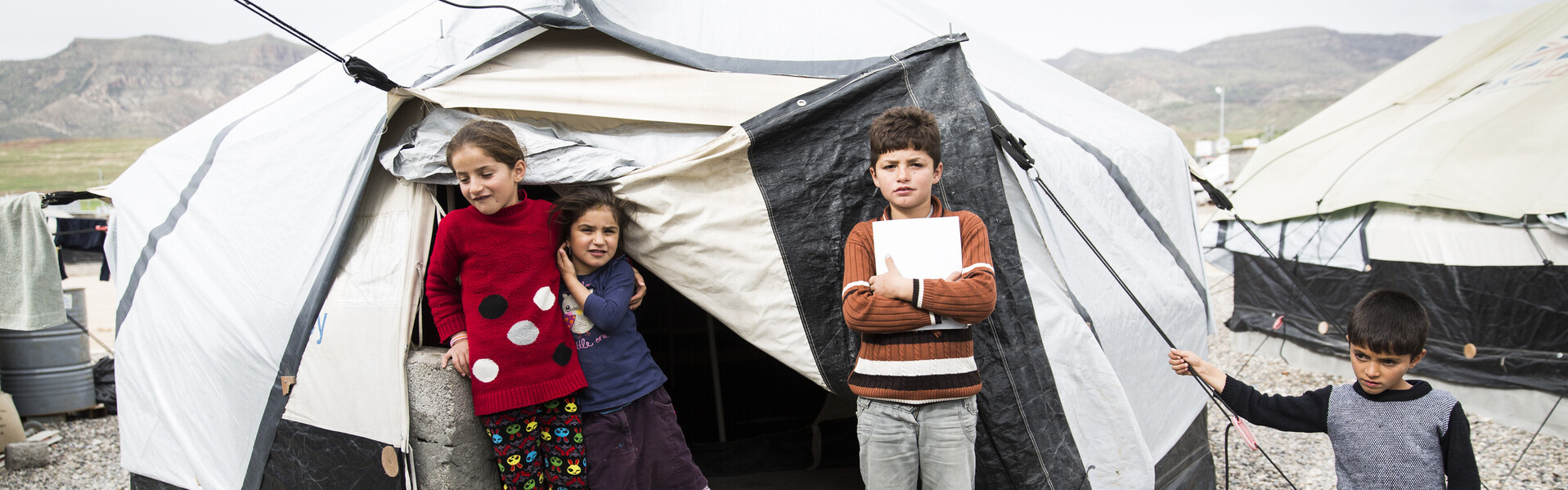 Kinder stehen vor einem Zelt in einem Flüchtlingslager im Irak.
