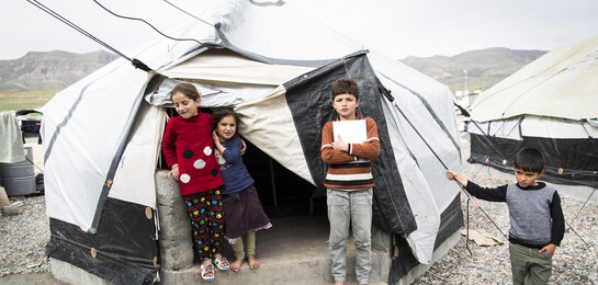 Kinder stehen vor einem Zelt in einem Flüchtlingslager im Irak.