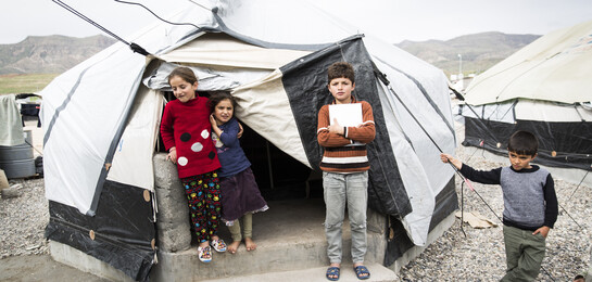 Kinder stehen vor einem Zelt in einem Flüchtlingslager im Irak.