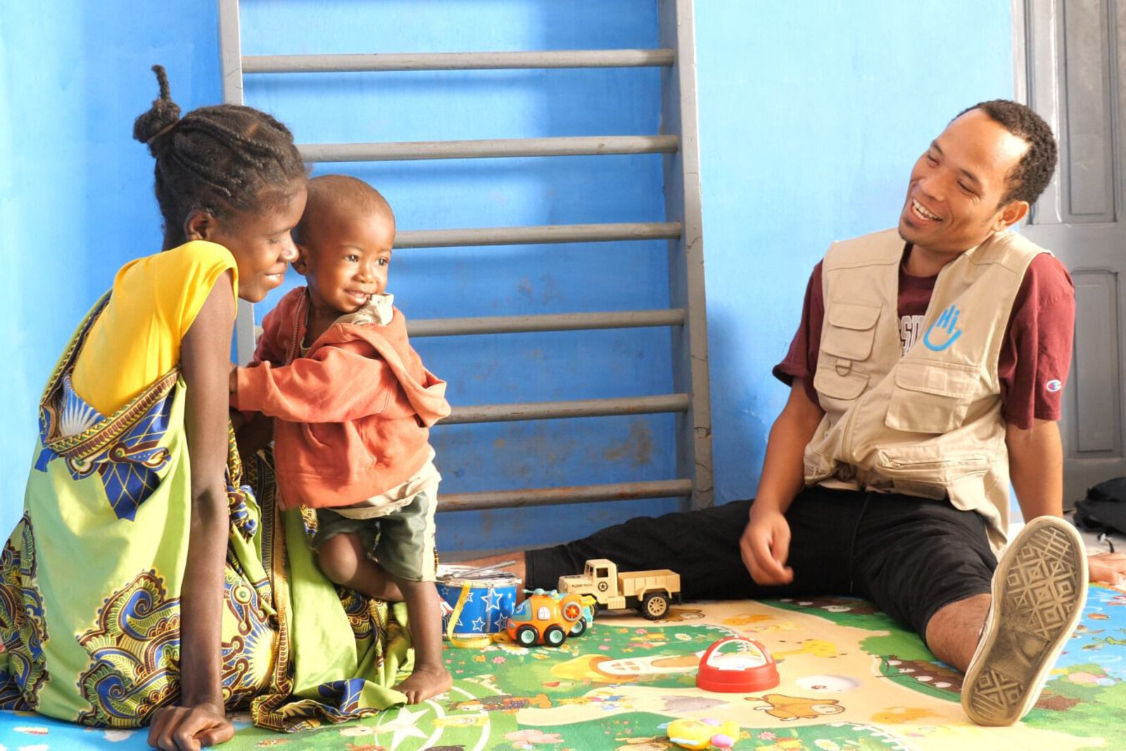 Ein Mitarbeiter von Handicap International bei einer Therapie mit Mutter und Kind 