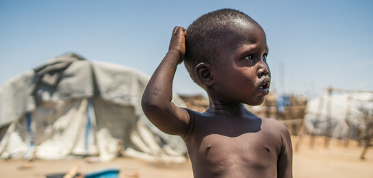 Ein Junge im Südsudan steht vor einem Flüchtlingszelt.