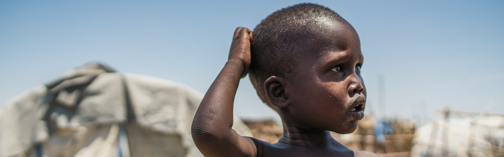 Ein Junge im Südsudan steht vor einem Flüchtlingszelt.